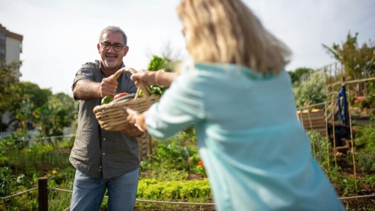A man handing a woman a basket full of produce.