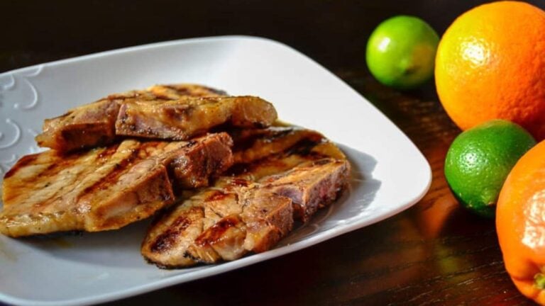 Grilled pork chops on a plate with oranges and limes.