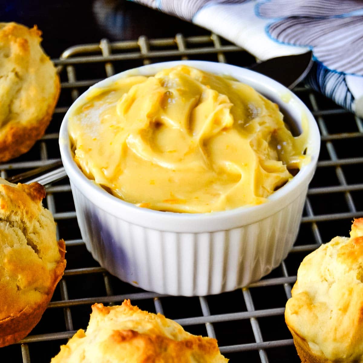 Clementine honey butter in a white ramaking sitting on a cooling rack next to drop biscuits.