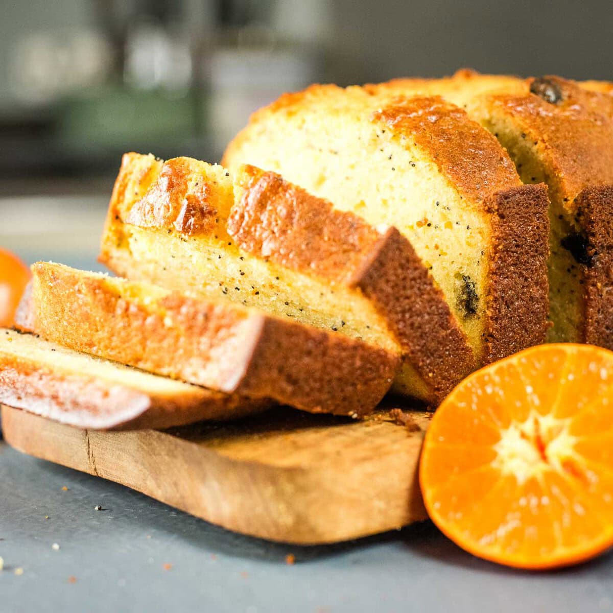 Sliced cranberry clementine bread on a cutting board with a halved clementine leaning against it.