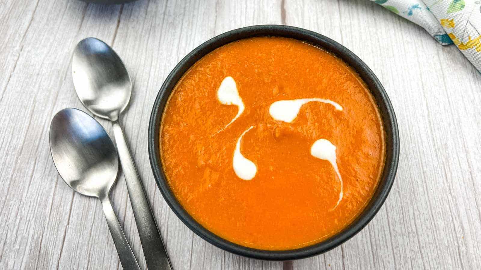 A bowl of oven-roasted tomato soup with two spoons.