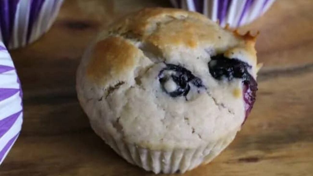 Blueberry muffin on a wooden serving board.