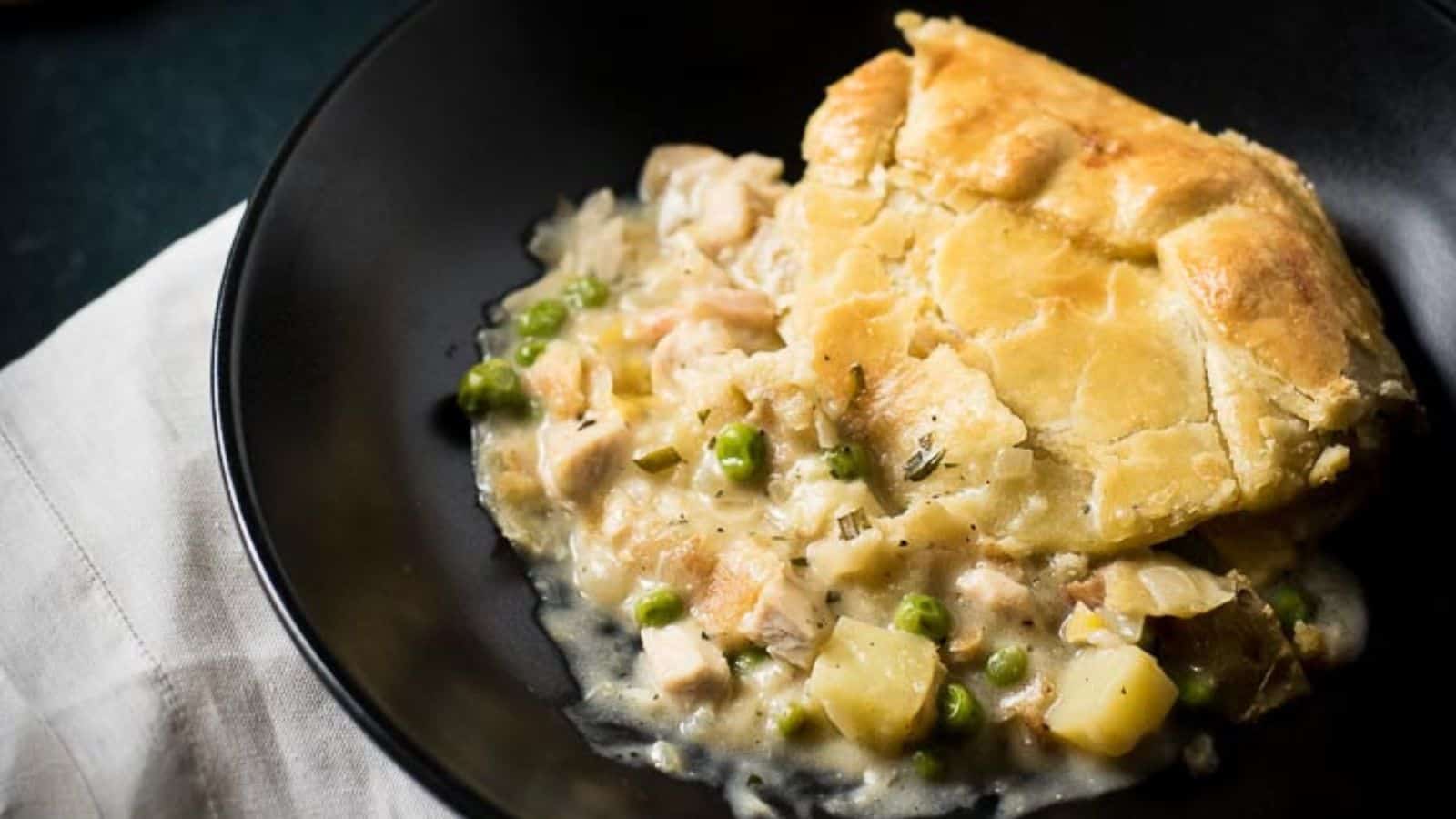 Closeup of chicken pot pie in a balack bowl.