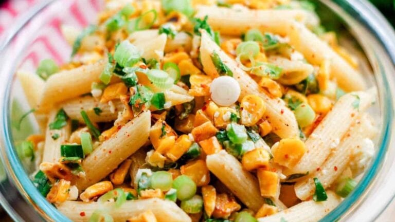 A bowl of Mexican Street Corn with a spoon in it ready to serve.