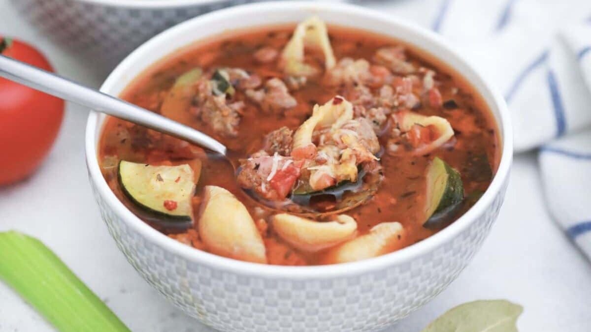 Minestrone Soup with Sausage in white bowl with spoonful.