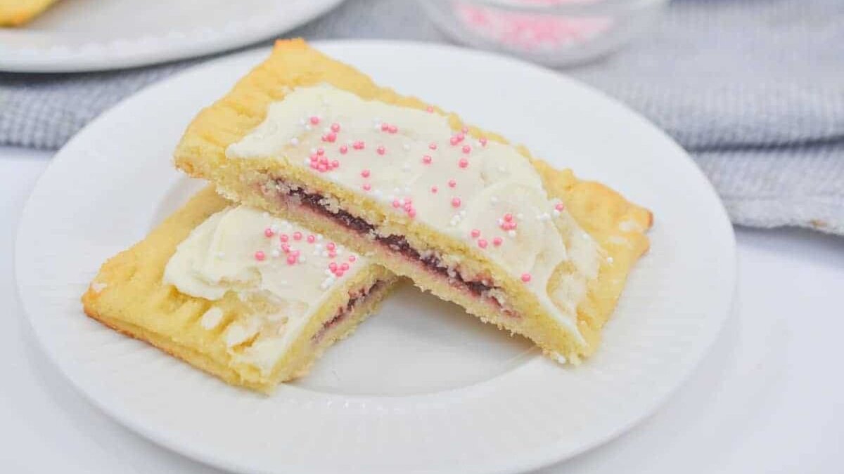 A plate with a slice of a cookie with frosting and sprinkles.