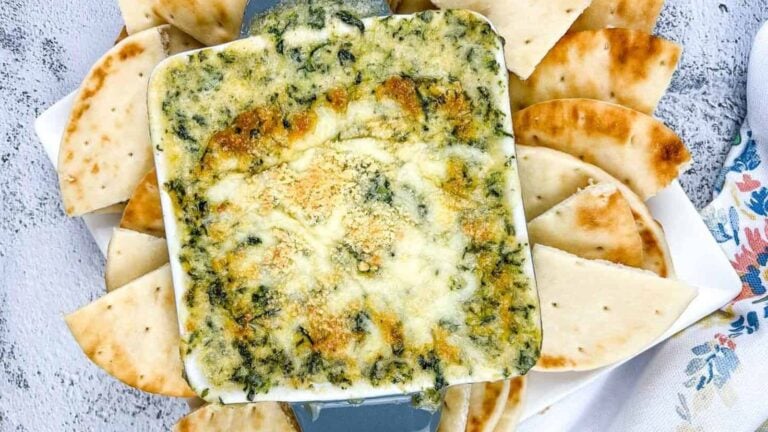 Spinach & Brie Dip in a casserole dish surrounded by pita wedges.