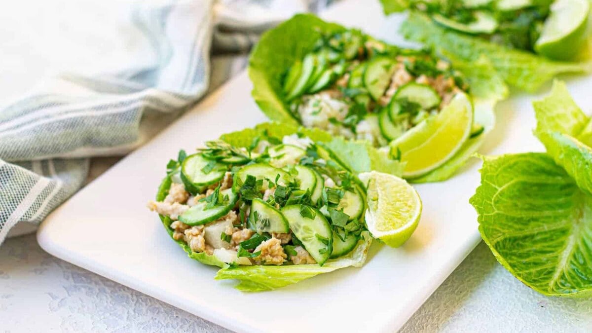 Thai chicken lettuce wraps with peanut sauce on a white plate.