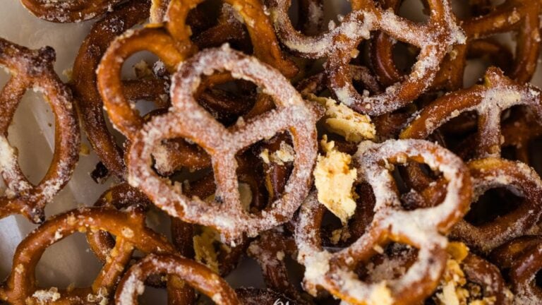 Close-up of salted pretzels with visible coarse salt and broken pieces scattered among whole pretzels.