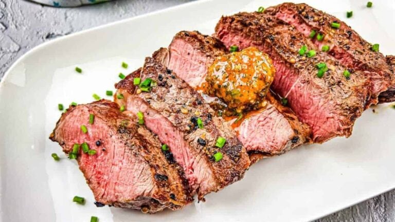 A grilled steak with cowboy butter on a white plate.