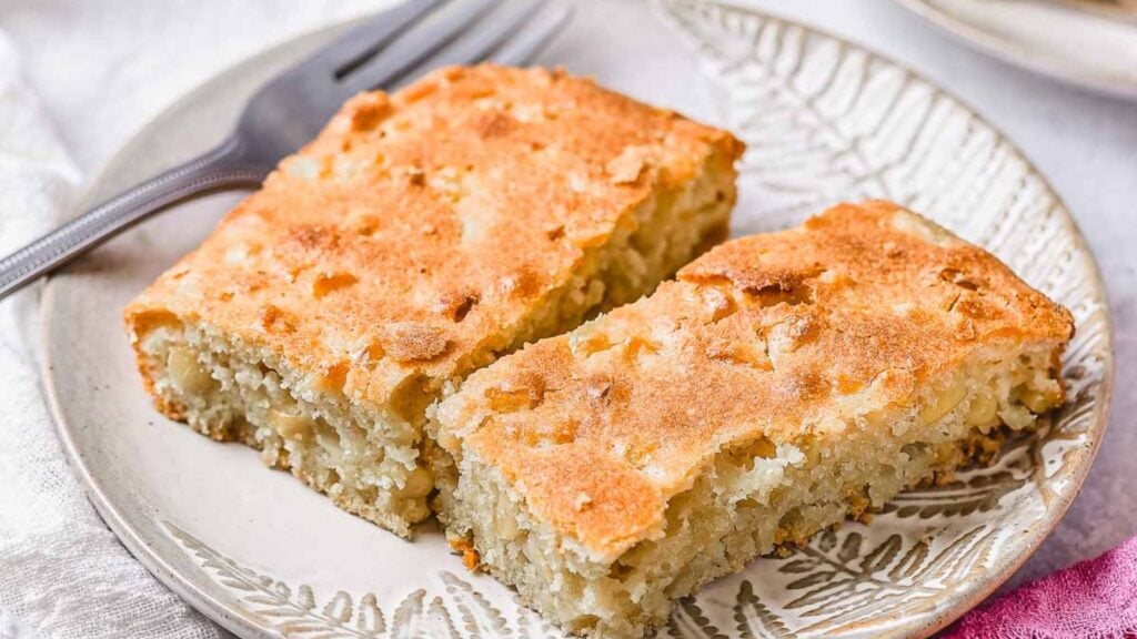 Two rectangular slices of light golden-brown cake with a slightly crumbly texture are placed side by side on a patterned plate.