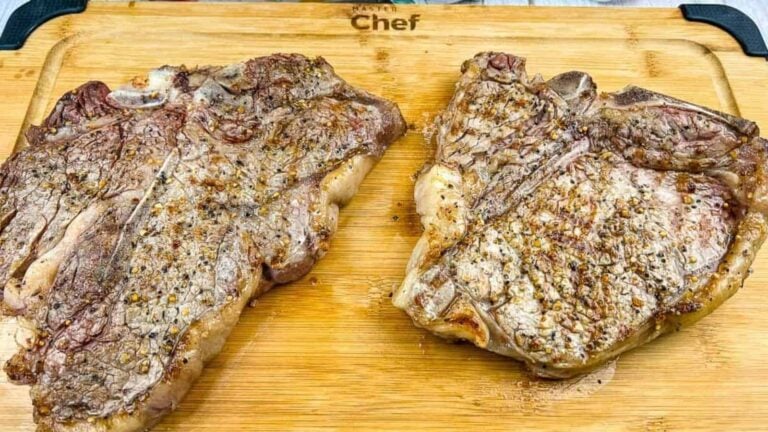 A grilled t-bone steak on a black platter.