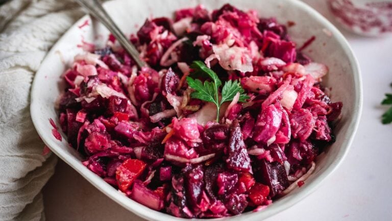 Russian vinaigrette salad with root vegetables and fresh herbs in a white bowl.