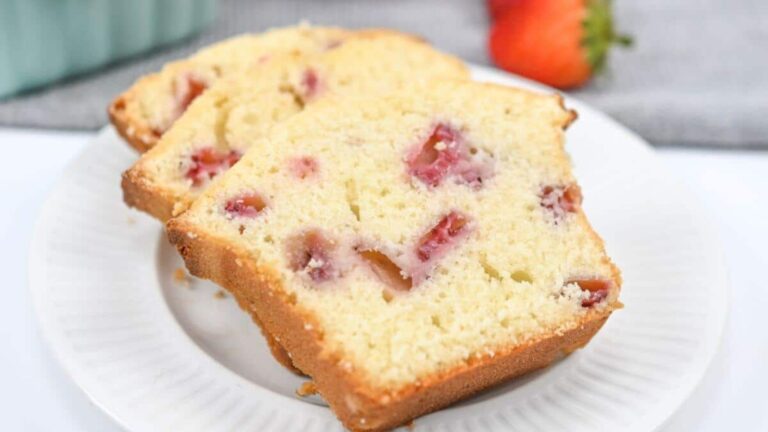 Two slices of strawberry bread with visible strawberry pieces are served on a white plate.