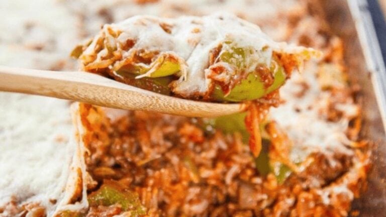 A spoon lifting out stuffed pepper casserole topped with mozzarella cheese.