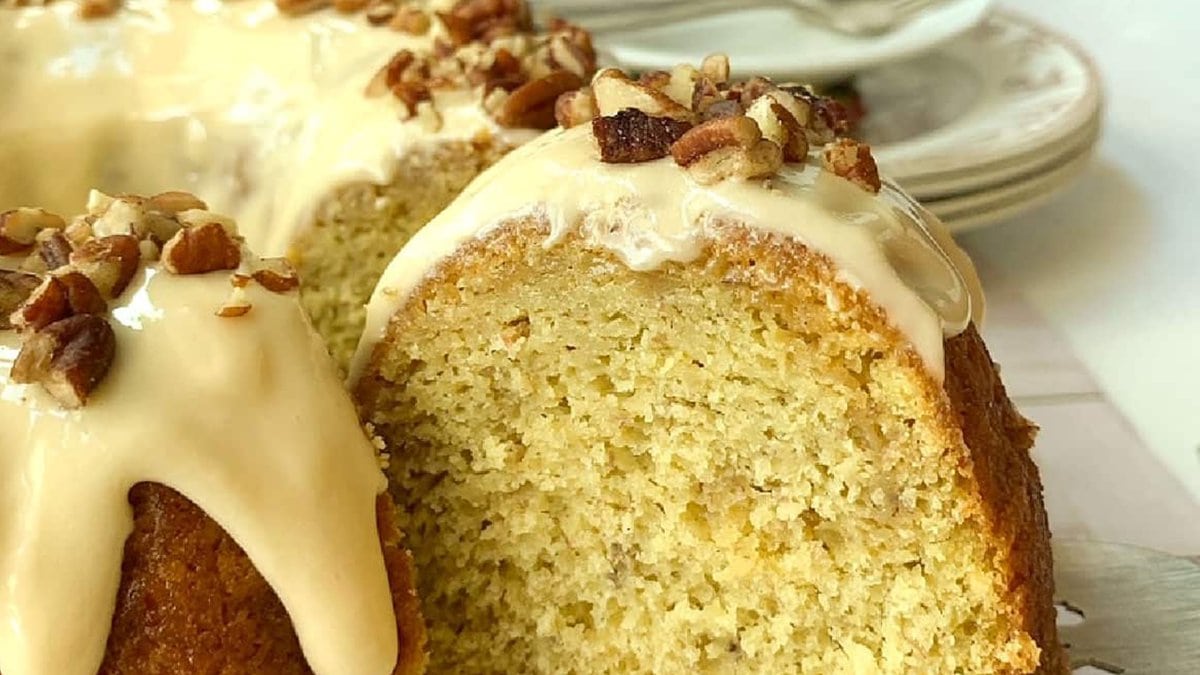 Iced banana cake with pecans on top.