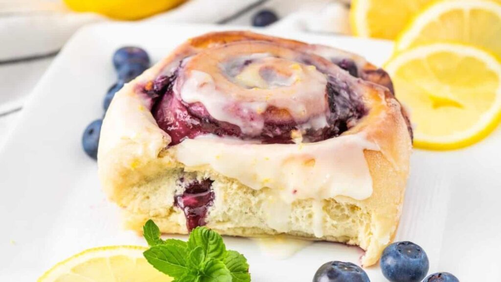 Lemon roll with blueberries on a plate.