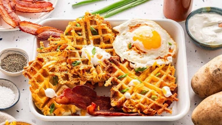 A tray full of waffles, bacons and sunny side up egg.