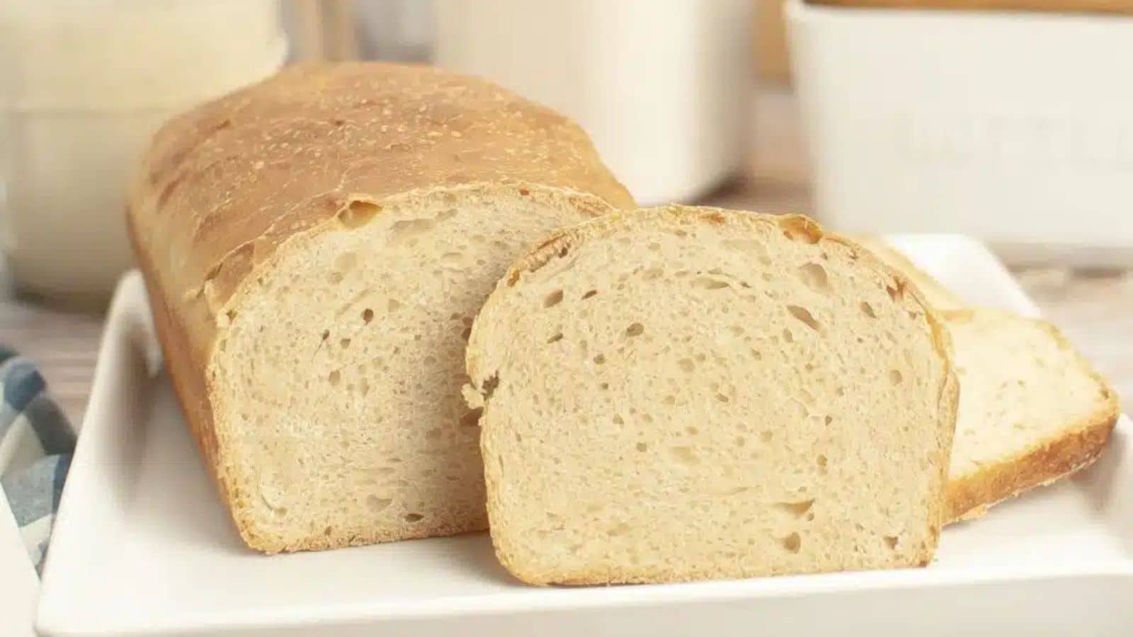 Loaf of bread with two slices cut on a white plate.