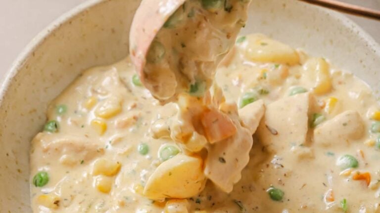 Chicken pot pie soup in a white bowl with a spoon.