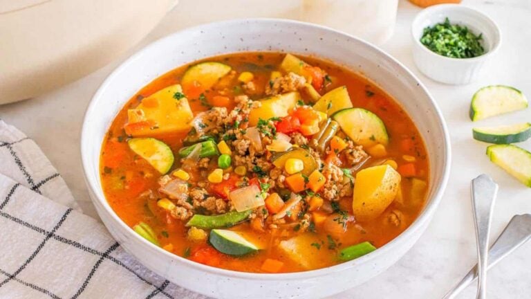 A bowl of ground turkey vegetable soup with potatoes, zucchini, peas, and carrots.