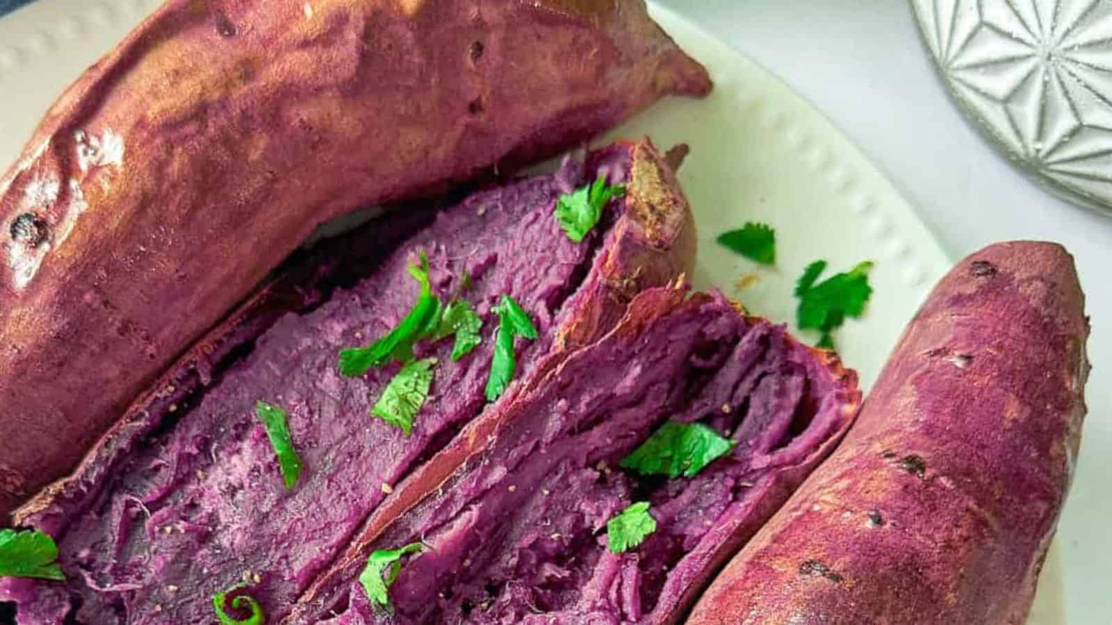 Sweet and creamy oven-roasted purple yams on a white plate with green onions.