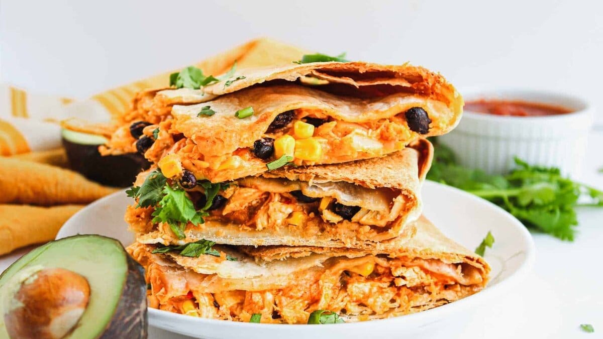 Stack of chicken quesadilla wedges with cilantro garnish.