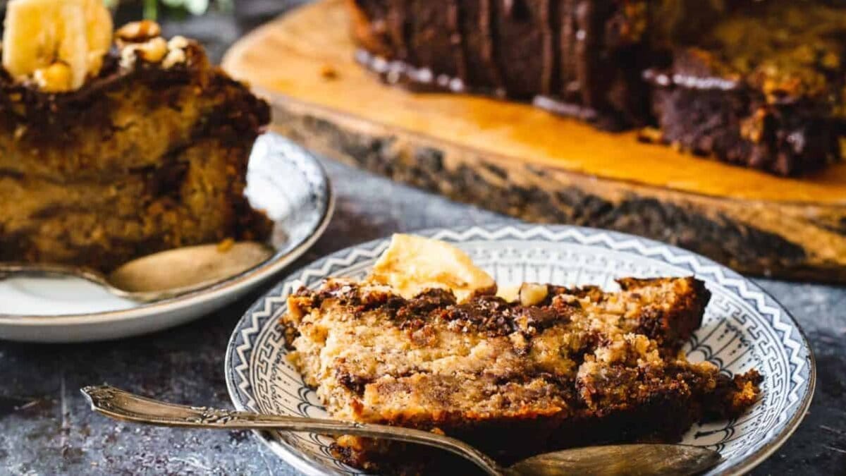 Two slices of chocolate banana bread with loaf in background.