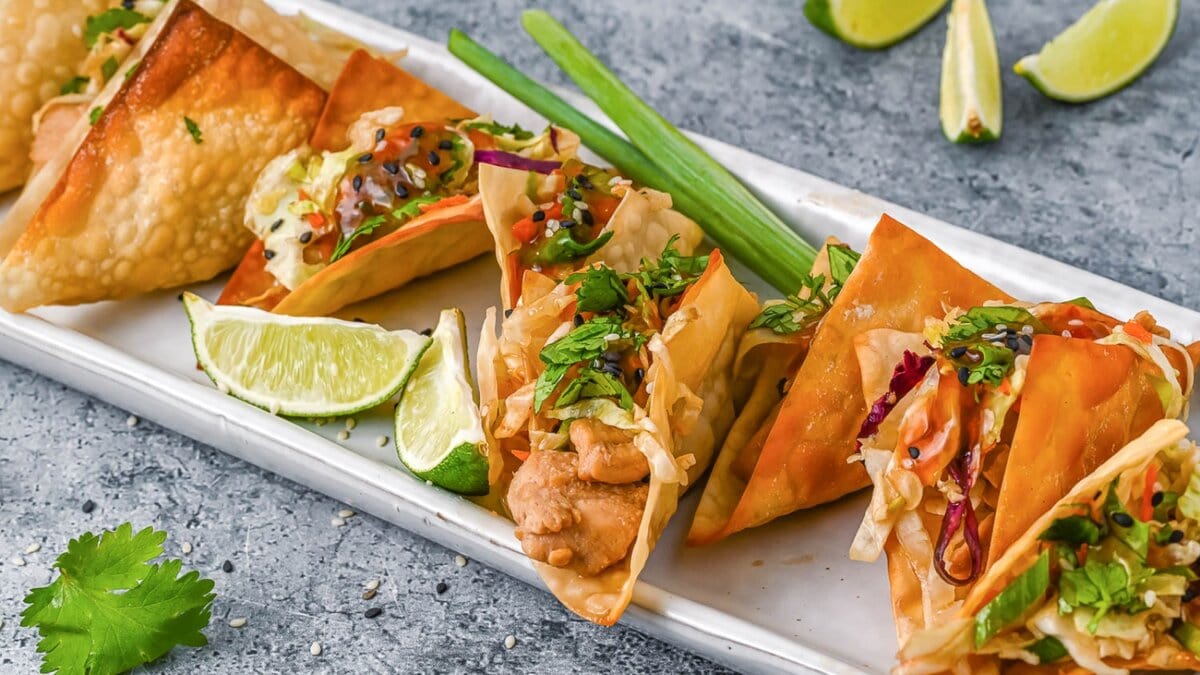 Long tray lined with wonton tacos and lime wedges.