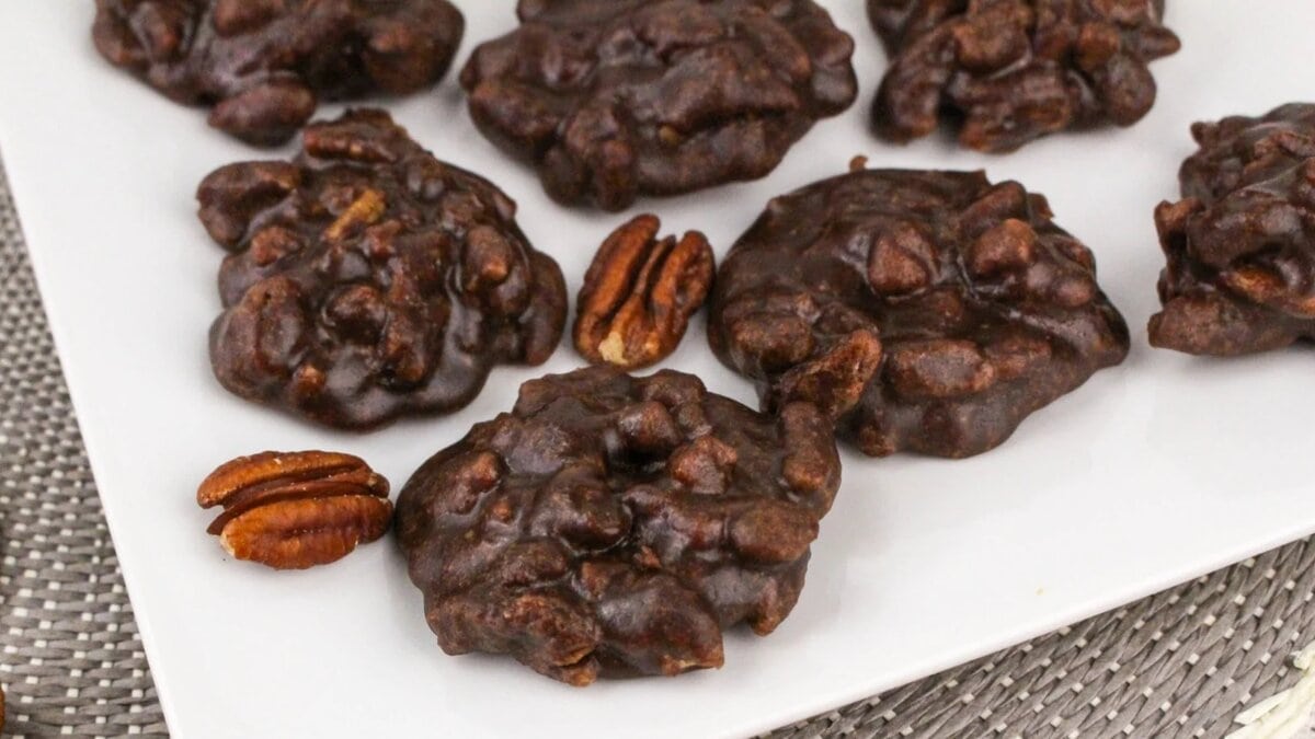 Chocolate pralines on a white plate, presented on a textured surface.