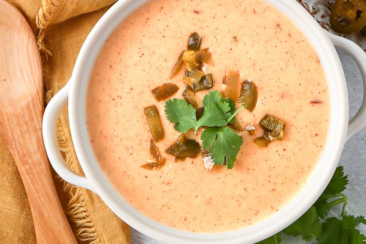 A bowl of creamy queso dip with a cheesy texture.