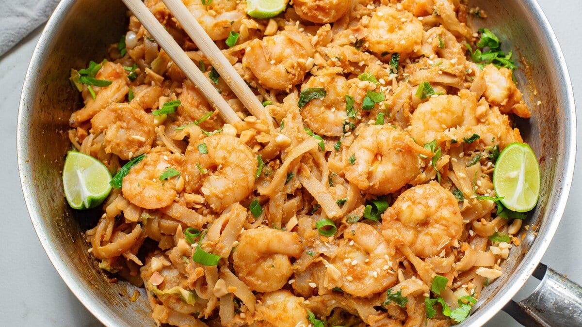 A pan full of shrimp and noodles with chopsticks.