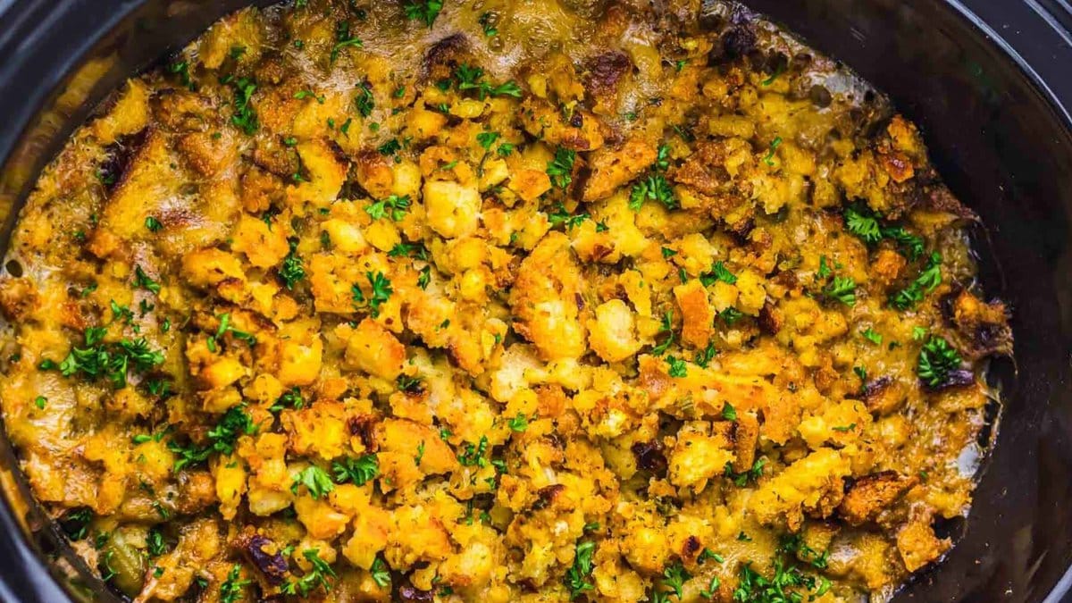 Golden-brown stuffing topped with chopped herbs, baked until crispy in a black dish.