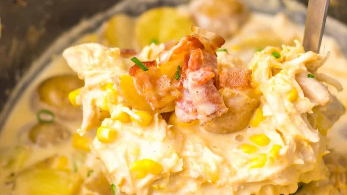 Close-up of a creamy chicken and corn chowder with chopped bacon and potatoes, garnished with fresh chives.