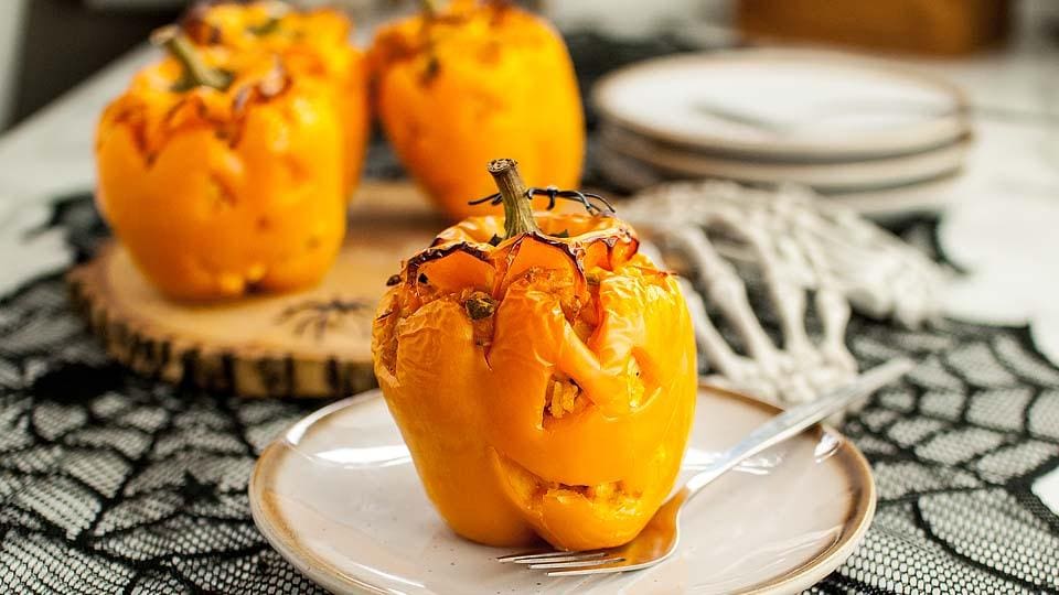 Jack-o’-lantern stuffed peppers filled with buffalo chicken and baked for a Halloween dinner.