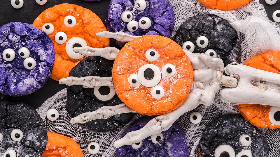 Halloween crinkle cookies topped with candy monster eyes on a cooling rack.