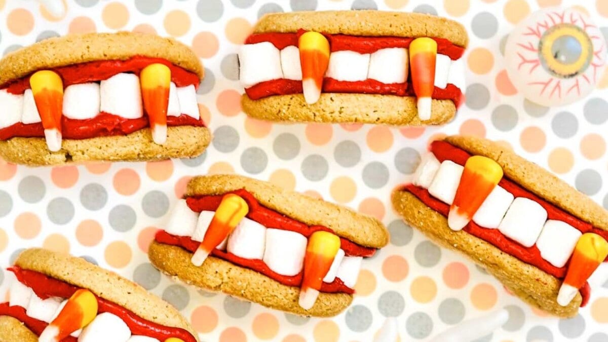 Five Halloween-themed cookie sandwiches resemble vampire mouths. The background features a polka dot pattern in pastel colors.