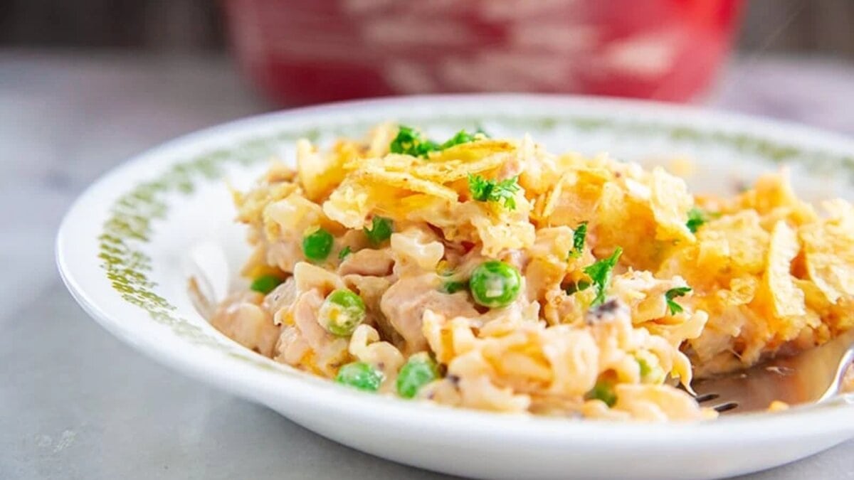 A plate of tuna casserole with noodles, peas, and a crispy topping, served on a white dish with a decorative green border.