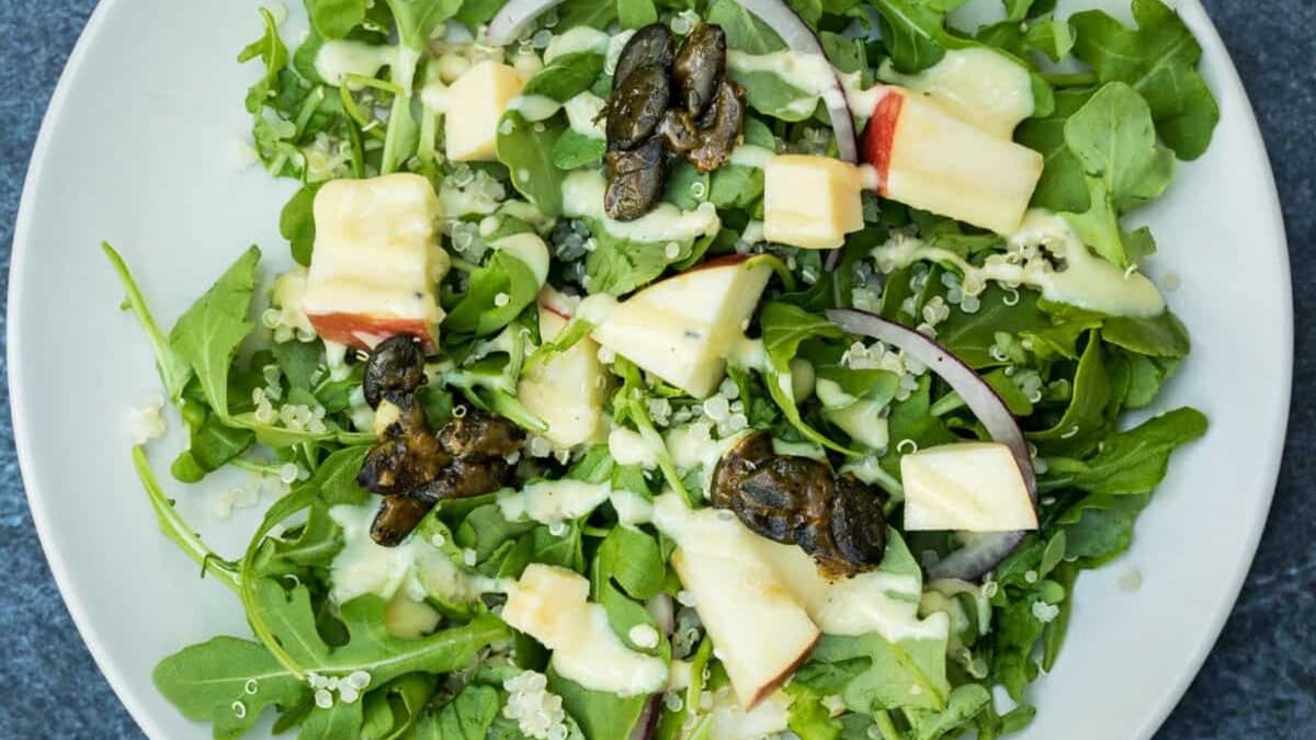 Arugula salad with apple slices, quinoa, red onion, and candied pepitas.