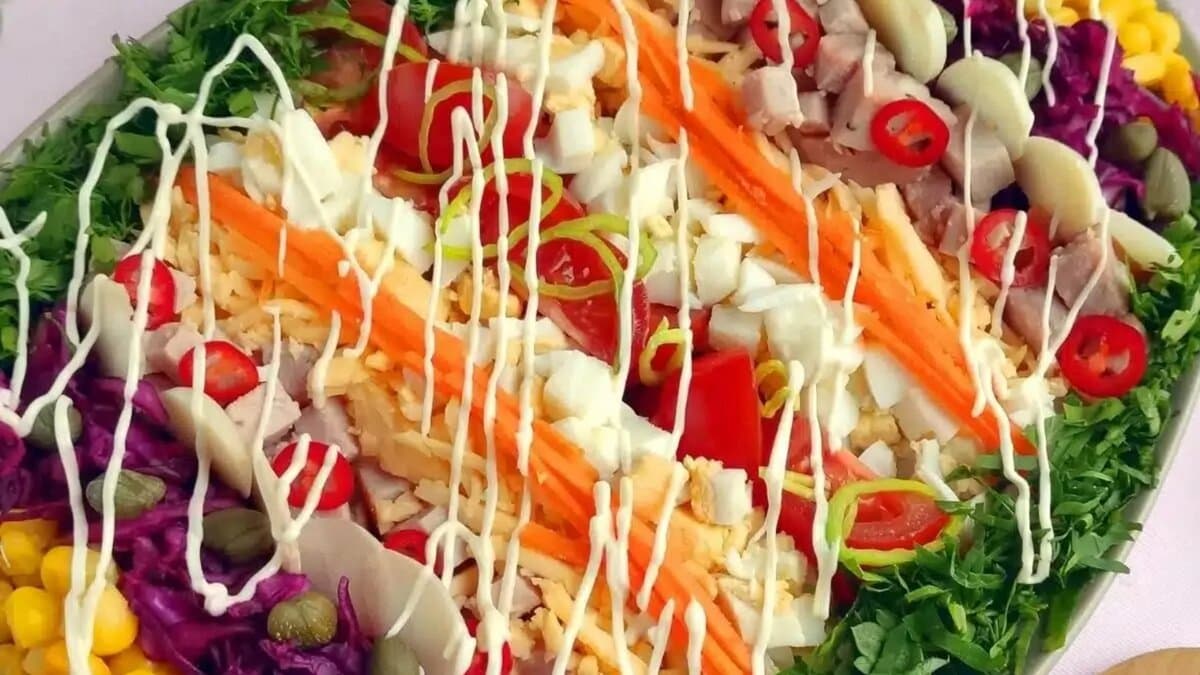 Easter egg&ndash;shaped layered salad decorated with colorful vegetables and toppings.