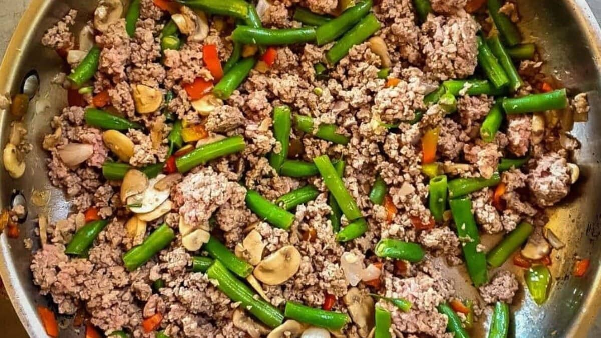 A picture of ground beef and green bean stir-fry in stainless steel skillet.