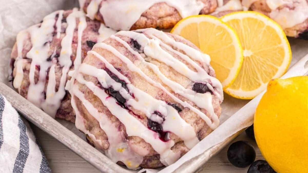 Iced blueberry cookies are arranged in a tray with lemon slices and whole blueberries beside them, adding a burst of spring color&mdash;perfect for Easter brunch recipes.