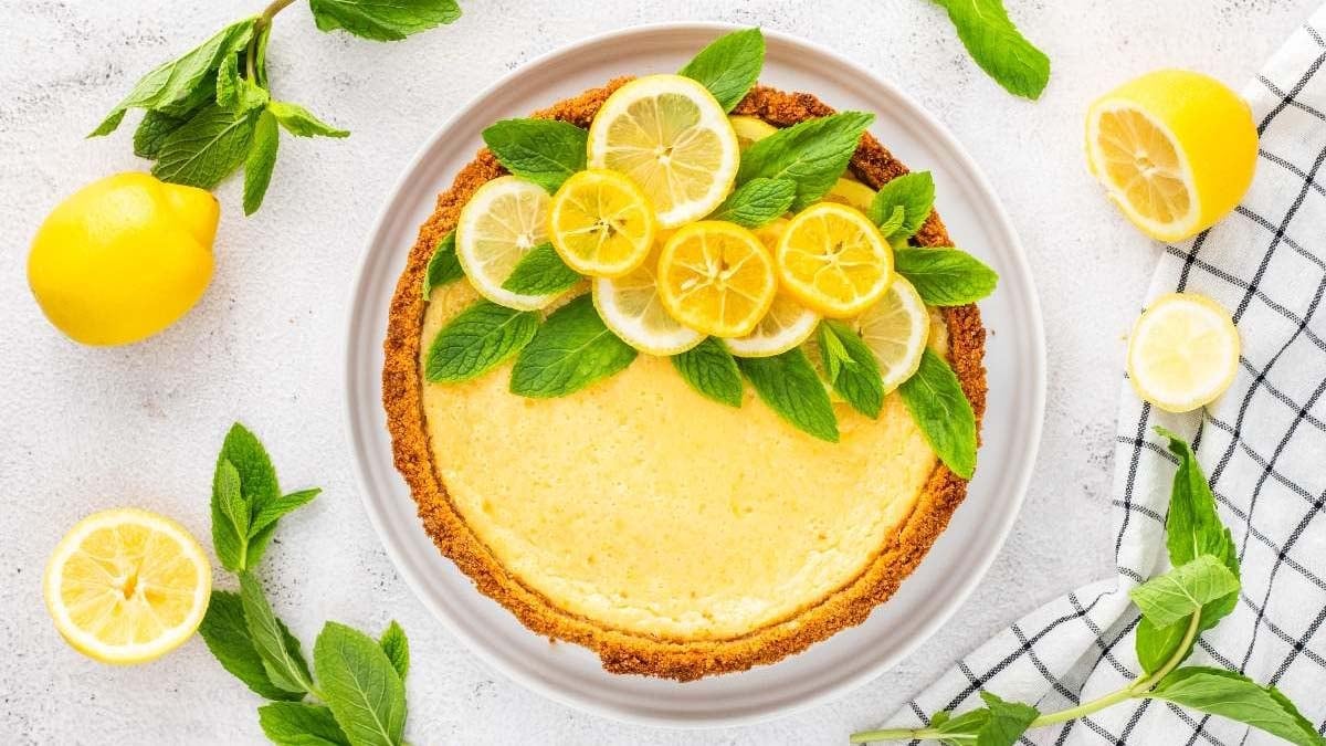Bright lemon tart topped with citrus slices and powdered sugar.