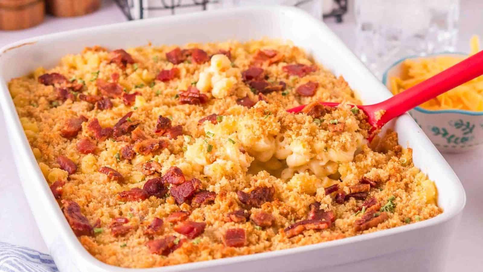 Baked macaroni and cheese topped with crispy breadcrumbs and bacon pieces in a white casserole dish.